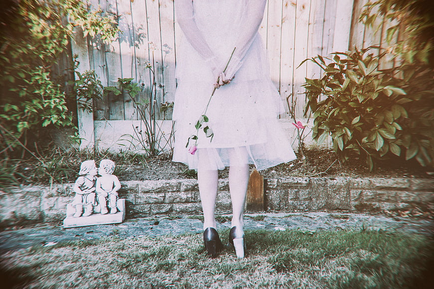 Woman in White Dress Holding Rose in Garden