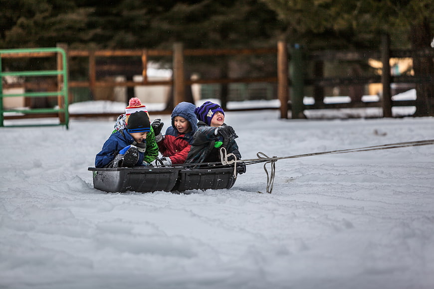 Children sledding together in winter snow