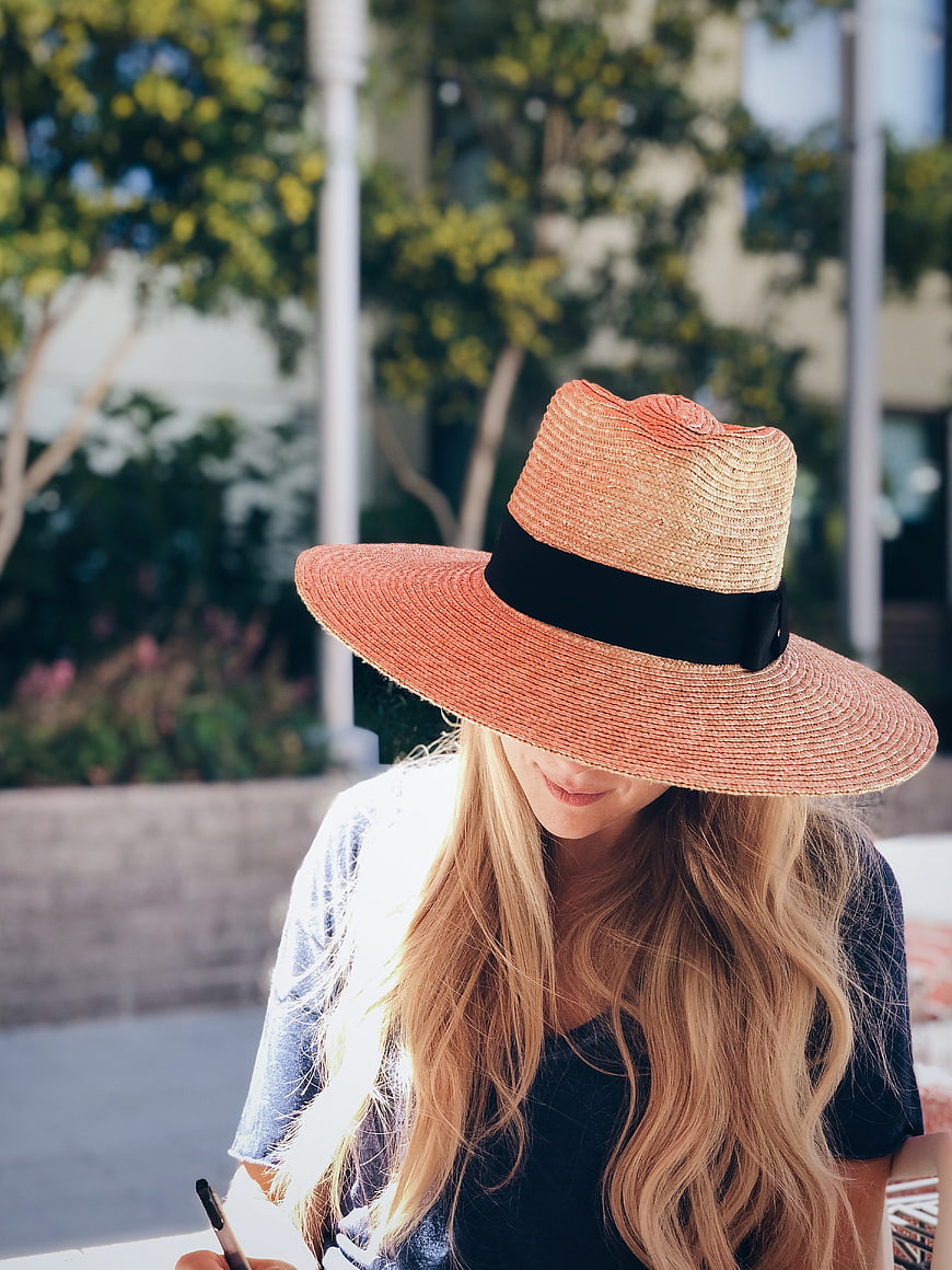 Blonde Woman in Straw Hat Writing Outdoors in Sunlight