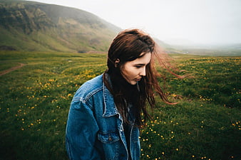 Woman in Denim Jacket Standing in Windy Mountain Meadow