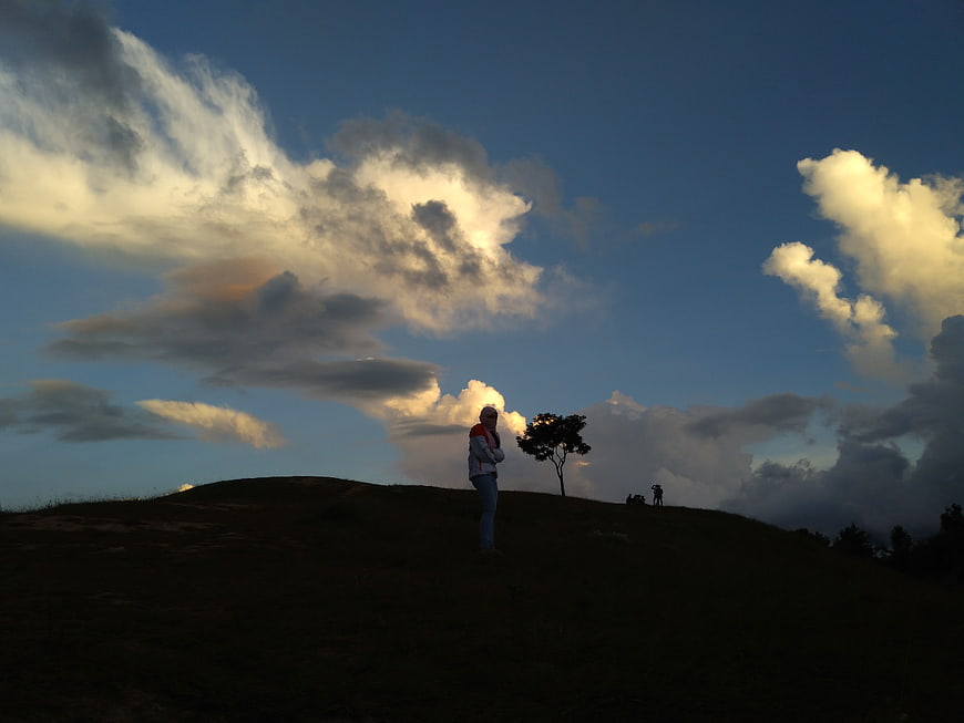 Silhouette of Person Standing on Hill Against Dramatic Clouds