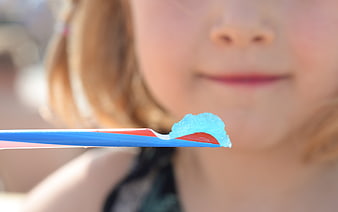 Close-up of blue slushy ice on a straw with blurred child