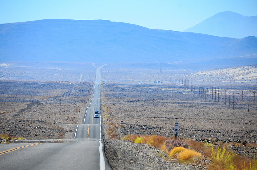 Long straight desert highway stretching to distant mountains