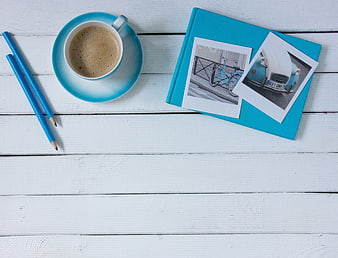 Coffee, Pencils, and Travel Photos on White Wooden Desk