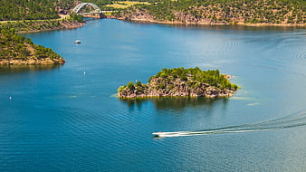 Aerial view of a rocky island in a blue lake with a bridge