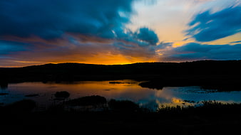 Dramatic sunset sky reflected in calm lake water