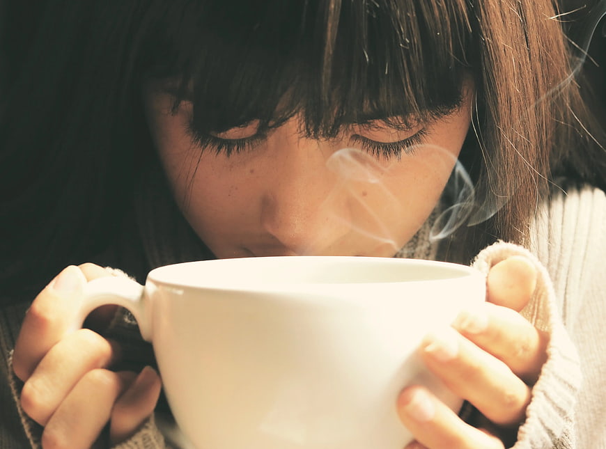 Woman Sipping Hot Coffee in Cozy Sweater