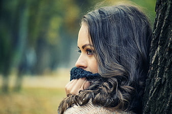 Pensive Woman Leaning Against Tree in Autumn Park
