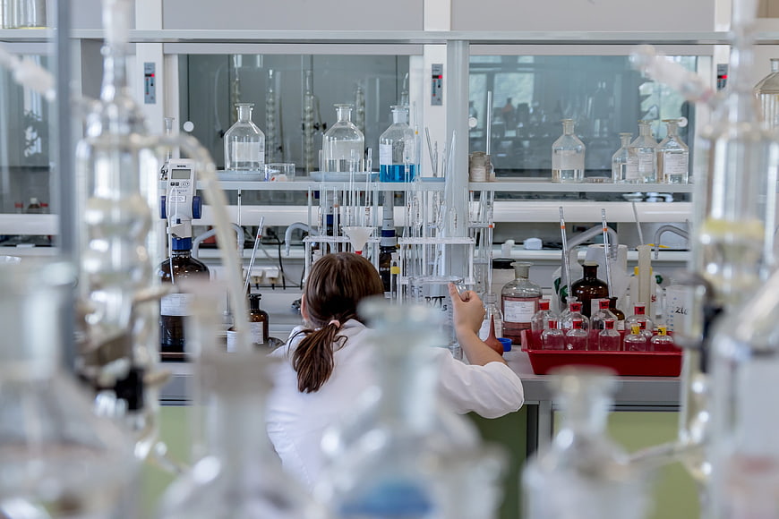 Female Chemist Working in Modern Laboratory with Glassware