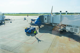 Blue Airplane Parked at Airport Gate with Ground Crew