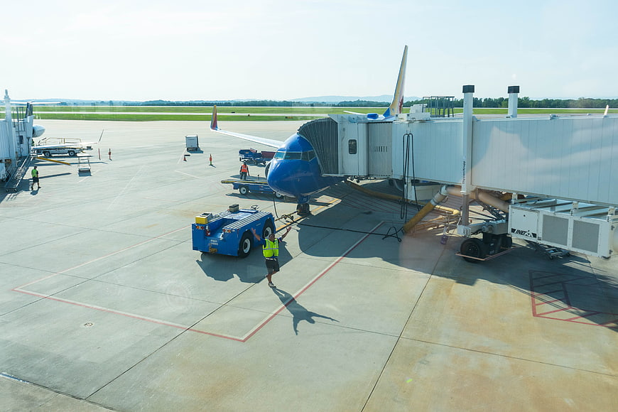 Blue Airplane Parked at Airport Gate with Ground Crew