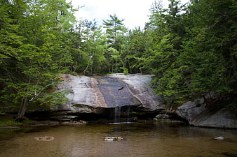 Small waterfall cascading over granite rock into forest pool