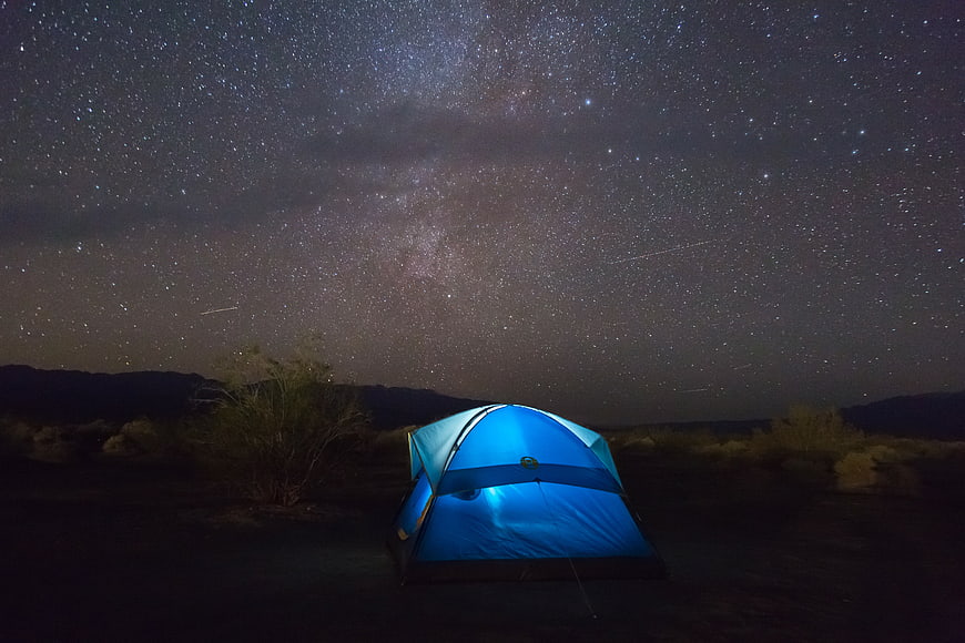 Blue camping tent under Milky Way night sky