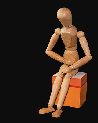 Wooden Mannequin Sitting on Orange Box with Stomach Pain