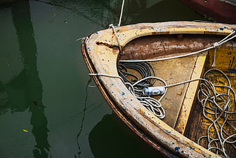 Weathered yellow boat with ropes and can on water
