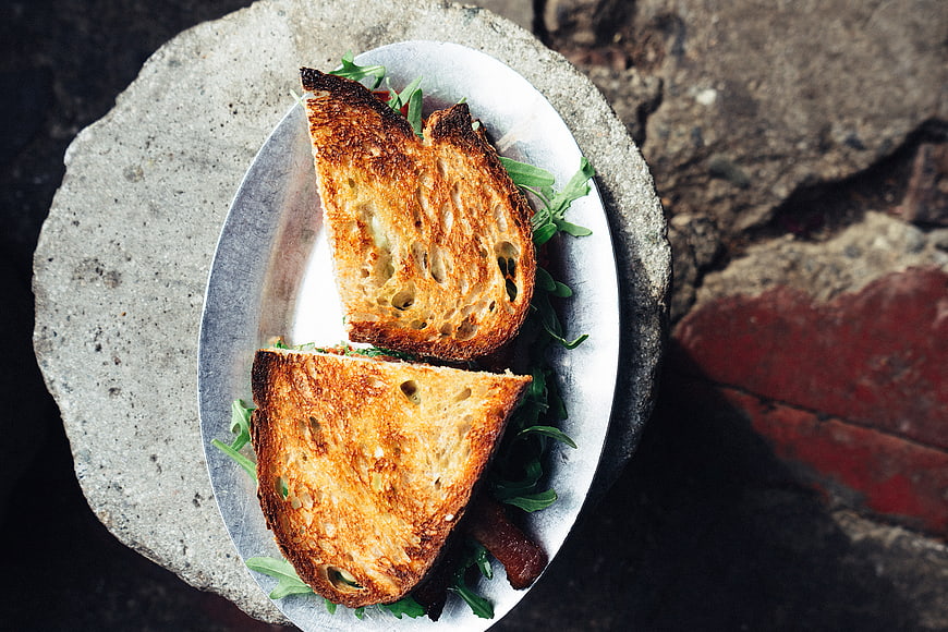Overhead view of toasted sandwich with arugula on rustic stone