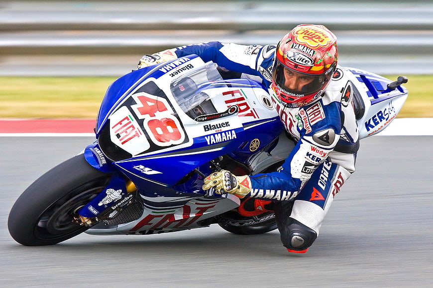 Motorcycle racer leaning into a turn on a race track