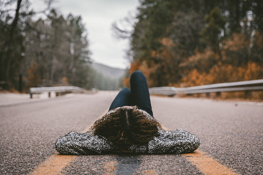 Woman lying on road in autumn forest