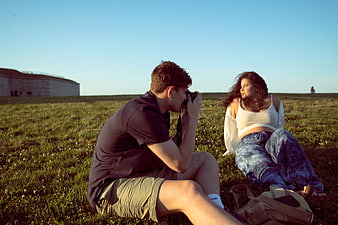 Photographer taking photos of model in grassy field
