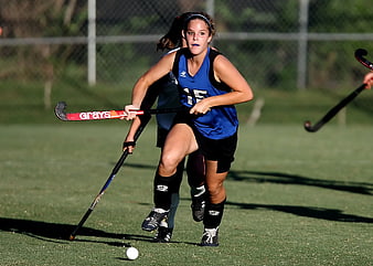 Female Field Hockey Player Dribbling Ball on Turf