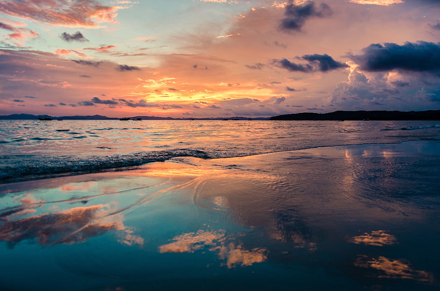 Vibrant Sunset Reflection on Wet Beach with Clouds