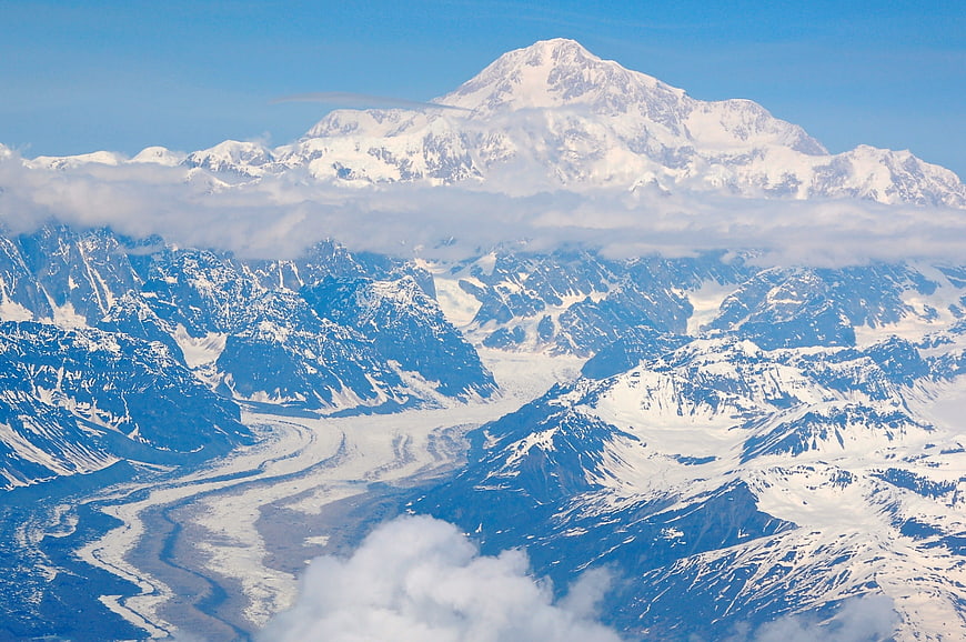 Aerial view of snow-capped mountain peak with glacier and clouds
