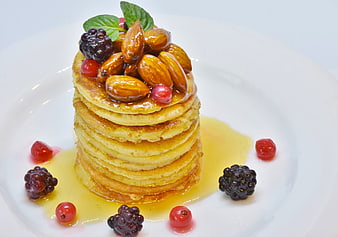 Stack of Pancakes with Almonds, Honey, and Berries on White Plate
