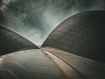 Dramatic low angle view of modern curved architecture against stormy sky