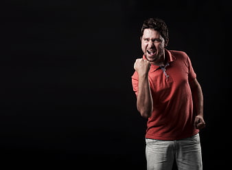 Excited man celebrating victory with fist pump on black background