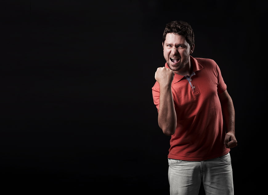 Excited man celebrating victory with fist pump on black background