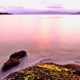 Long Exposure Pink Sunset Over Mossy Coastal Rocks