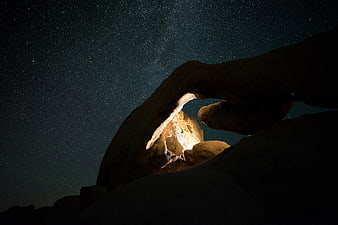 Natural rock arch under starry night sky with Milky Way