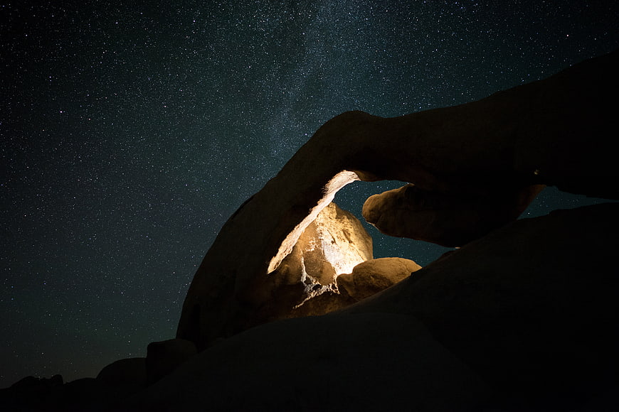 Natural rock arch under starry night sky with Milky Way