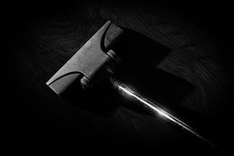 Black and white close-up of a vacuum cleaner nozzle on dark wood
