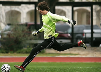 Soccer Goalkeeper Kicking Ball on Green Field
