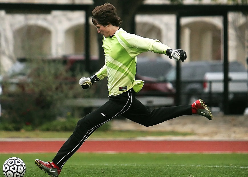 Soccer Goalkeeper Kicking Ball on Green Field