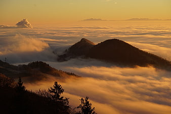 Golden sunrise over mountains rising above a sea of fog