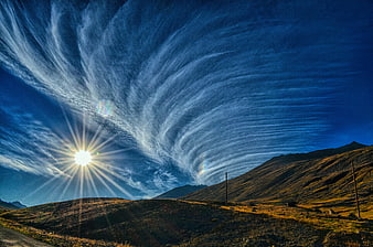 Dramatic Cirrus Clouds Over Mountain Landscape at Sunset