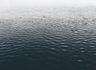 Calm Ocean Water Surface with Gentle Ripples and Misty Horizon