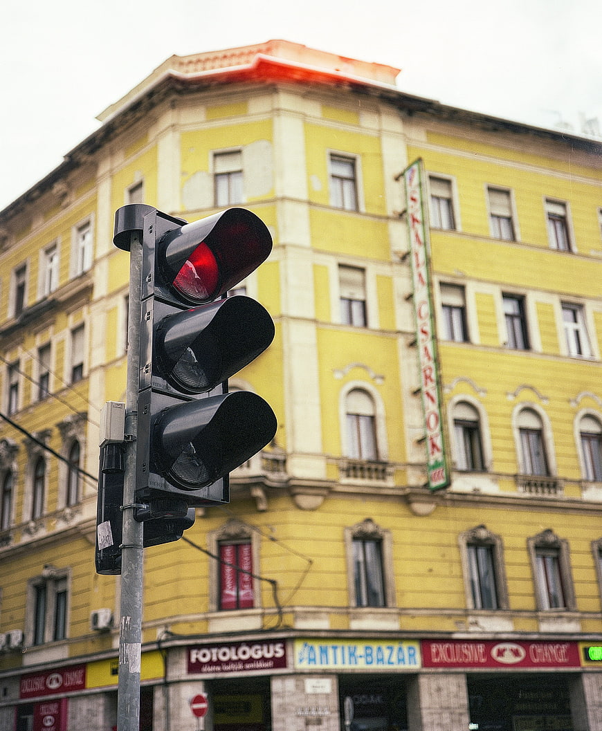 Red Traffic Light in Front of Yellow Building