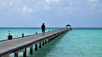 Person Walking on Wooden Pier in Turquoise Maldives Lagoon
