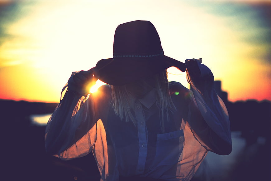 Woman in Hat Silhouette Against Golden Sunset Sky