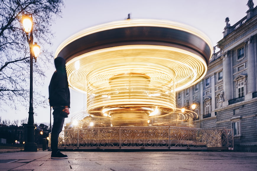 Long Exposure of Spinning Carousel at Night with Man Watching