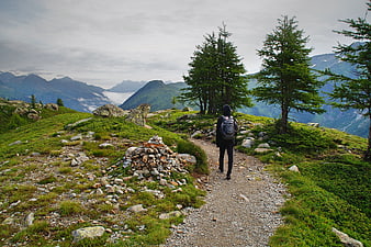 Hiker walking on mountain trail with backpack and scenic view