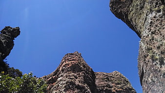Low angle view of rugged rock formations against blue sky