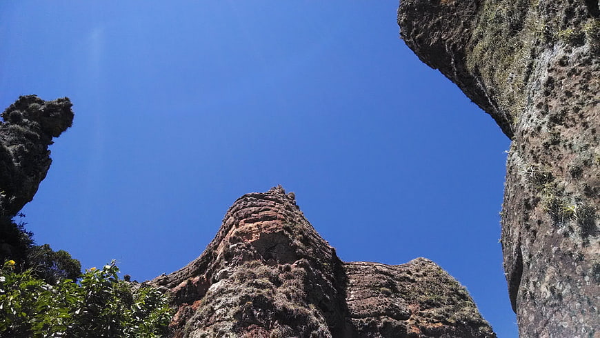 Low angle view of rugged rock formations against blue sky
