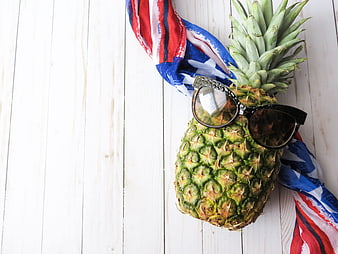Pineapple with sunglasses and American flag on white wood