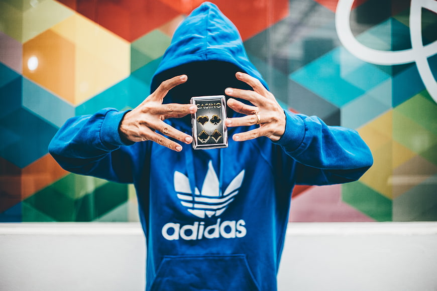 Anonymous man in blue hoodie holding playing cards