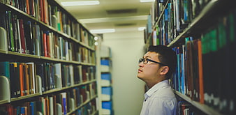 Man looking at books in a library aisle