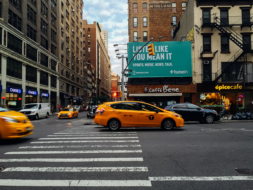 Yellow Taxi Driving Through New York City Street Intersection